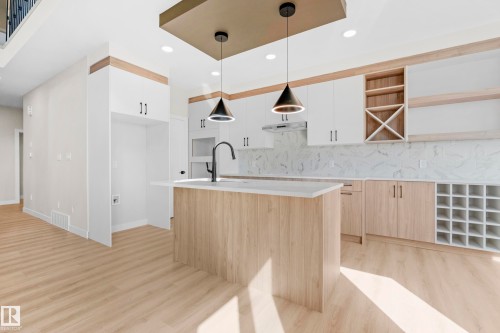 Contemporary kitchen featuring a central island with a light wood-finish base and light-toned countertop - 4915 17 Avenue, Edmonton, AB - Indoor