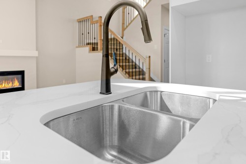 Kitchen island featuring a dual-basin undermount sink, gooseneck faucet with pull-down spray, and a white countertop - 4915 17 Avenue, Edmonton, AB - Indoor Photo Showing Kitchen With Double Sink