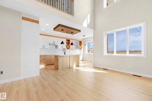 Open-concept interior featuring light wood-finish flooring, a two-story ceiling, and large windows - 4915 17 Avenue, Edmonton, AB - Indoor Photo Showing Other Room