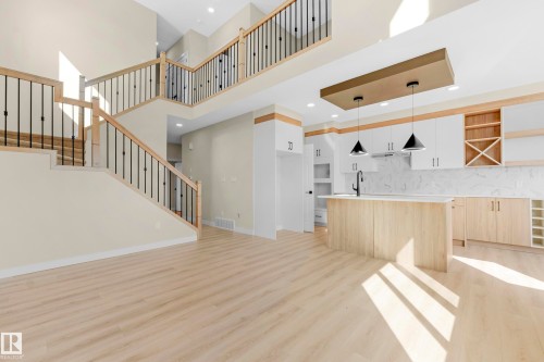 Two-story ceiling height entry featuring light wood-finish flooring and an open-concept kitchen - 4915 17 Avenue, Edmonton, AB - Indoor Photo Showing Other Room