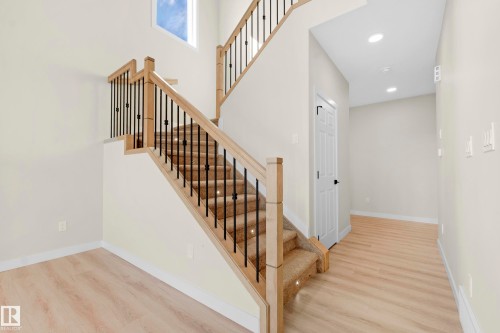 Two-story staircase featuring wood newel posts, handrails, and black metal balusters - 4915 17 Avenue, Edmonton, AB - Indoor Photo Showing Other Room