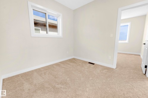 Carpeted room featuring a white-trimmed window, neutral wall paint, and white baseboards - 4915 17 Avenue, Edmonton, AB - Indoor Photo Showing Other Room