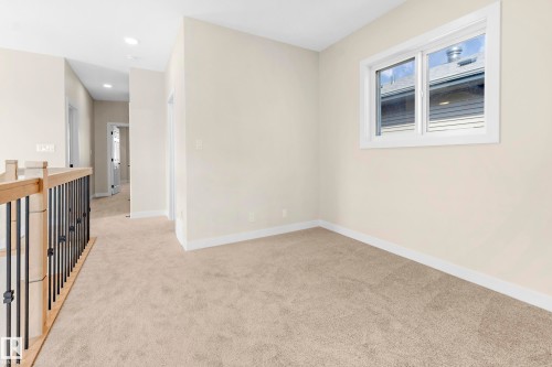 Carpeted loft area with a contemporary wood and metal railing - 4915 17 Avenue, Edmonton, AB - Indoor Photo Showing Other Room