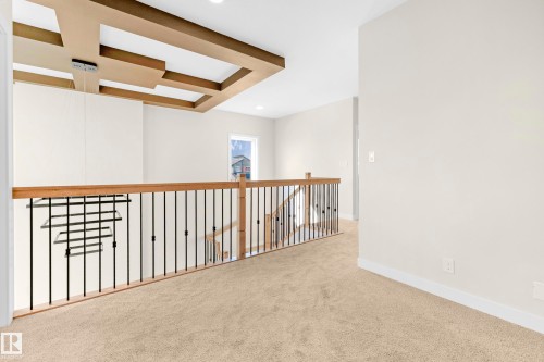 Upper level landing featuring light beige carpeting, white walls, a decorative coffered ceiling with recessed lighting, and a window providing natural light - 4915 17 Avenue, Edmonton, AB - Indoor Photo Showing Other Room