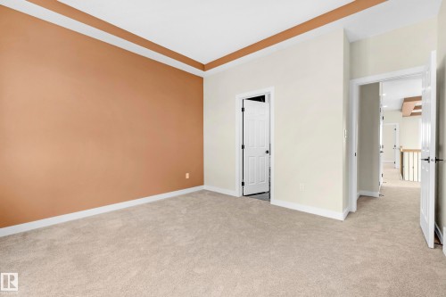 Carpeted room featuring a tray ceiling, a neutral color palette, white baseboards, and multiple doorways - 4915 17 Avenue, Edmonton, AB - Indoor Photo Showing Other Room