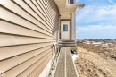 Side exterior featuring neutral-toned horizontal siding, a white entry door with divided lites, an overhead soffit, and a foundational ramp - 4915 17 Avenue, Edmonton, AB  - Outdoor 