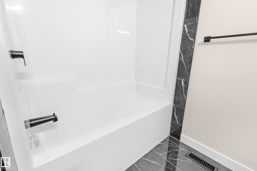 White acrylic tub/shower combination with matte black fixtures - 4915 17 Avenue, Edmonton, AB - Indoor Photo Showing Bathroom