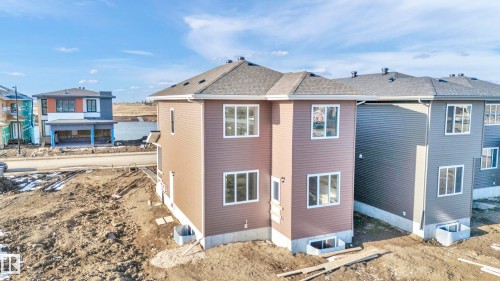 Two-story exterior with brown siding, white-framed windows, and a dark shingle roof - 4915 17 Avenue, Edmonton, AB - Outdoor