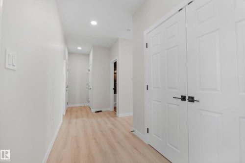 Hallway featuring contemporary white paneled doors with black hardware, recessed ceiling lighting, and light wood-finish flooring - 4915 17 Avenue, Edmonton, AB - Indoor Photo Showing Other Room