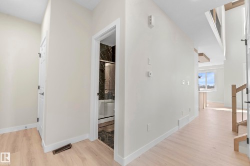 Light wood-finish flooring extends throughout this spacious hallway, featuring white walls and trim - 4915 17 Avenue, Edmonton, AB - Indoor Photo Showing Other Room