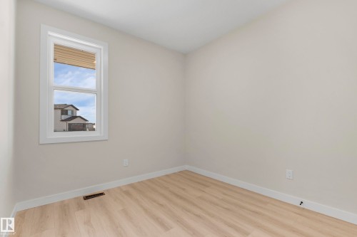 Light-colored walls featuring a white-trimmed window, wood-finish flooring, and white baseboards - 4915 17 Avenue, Edmonton, AB - Indoor Photo Showing Other Room