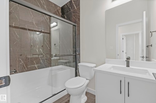 Contemporary bathroom featuring a white vanity with integrated sink, matte black hardware, and a framed mirror - 4915 17 Avenue, Edmonton, AB - Indoor Photo Showing Bathroom