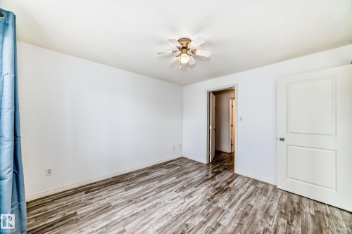 Spacious room featuring wood-finish flooring, white walls, and a ceiling fan with integrated lighting - 210 2305 35A Avenue, Edmonton, AB - Indoor Photo Showing Other Room