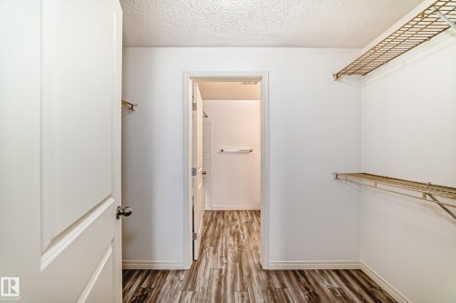 Walk-in closet featuring wire shelving, white painted walls, and wood-finish flooring - 210 2305 35A Avenue, Edmonton, AB - Indoor