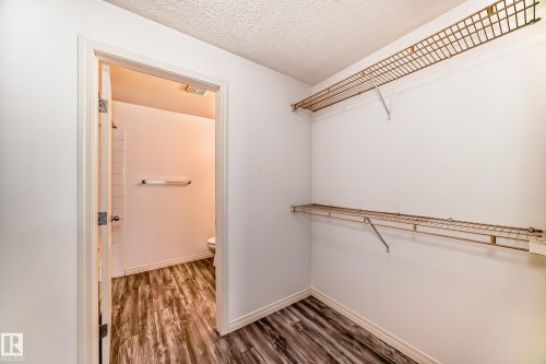 Walk-in closet featuring two levels of wire shelving and wood-finish flooring - 210 2305 35A Avenue, Edmonton, AB - Indoor With Storage