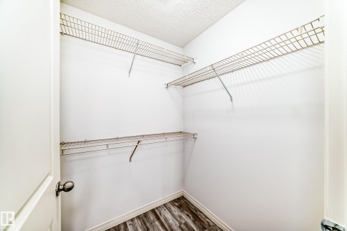 Walk-in closet featuring white painted walls, wire shelving, and wood-finish flooring - 210 2305 35A Avenue, Edmonton, AB - Indoor With Storage