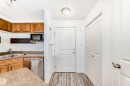 Kitchen area featuring wood cabinetry, stainless steel dishwasher, and microwave - 210 2305 35A Avenue, Edmonton, AB  - Indoor Photo Showing Kitchen With Double Sink 