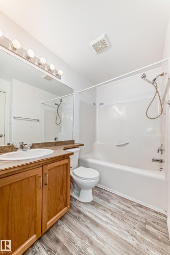 Bathroom featuring a single vanity with wood cabinetry, a white drop-in sink, and a brown speckled countertop - 210 2305 35A Avenue, Edmonton, AB - Indoor Photo Showing Bathroom