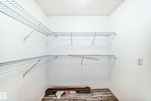 Walk-in closet featuring wire shelving, white walls, and wood-finish flooring - 210 2305 35A Avenue, Edmonton, AB - Indoor With Storage