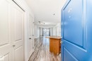 Entryway featuring a bright blue door, wood-finish flooring, two white panel doors, and a built-in wood-tone island with a light-colored countertop - 210 2305 35A Avenue, Edmonton, AB  - Indoor Photo Showing Other Room 