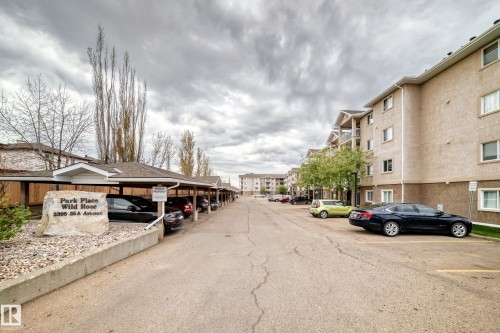 Apartment building exterior featuring multiple levels, balconies, and an adjacent covered parking structure - 210 2305 35A Avenue, Edmonton, AB - Outdoor