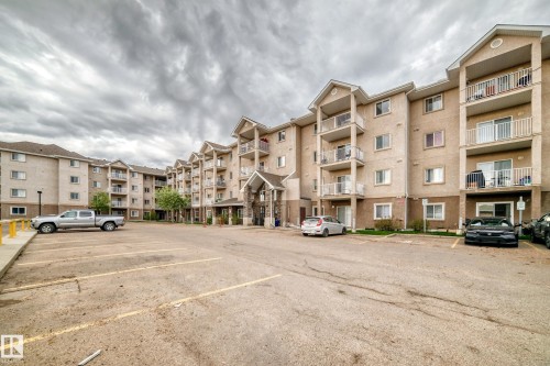 Multi-story residential building with a stucco exterior and stone facade accents - 210 2305 35A Avenue, Edmonton, AB - Outdoor With Facade