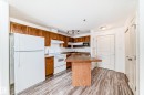 Kitchen featuring wood-finish cabinetry, white appliances, and a wood-finish island with an extended countertop - 210 2305 35A Avenue, Edmonton, AB  - Indoor Photo Showing Kitchen 