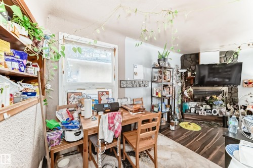 This living area features a stone-clad fireplace and wood-look flooring - 7723 82 Avenue, Edmonton, AB - Indoor Photo Showing Other Room