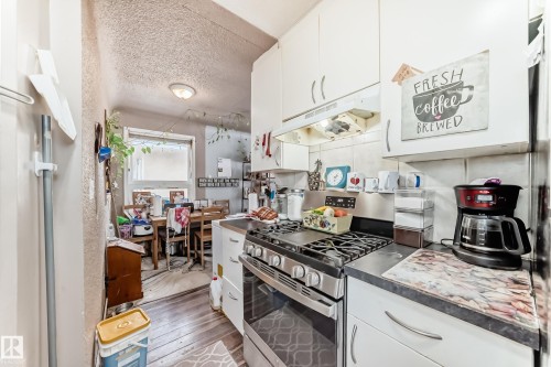The kitchen features white cabinetry, a gas range with a stainless steel finish, and dark countertops - 7723 82 Avenue, Edmonton, AB - Indoor Photo Showing Kitchen