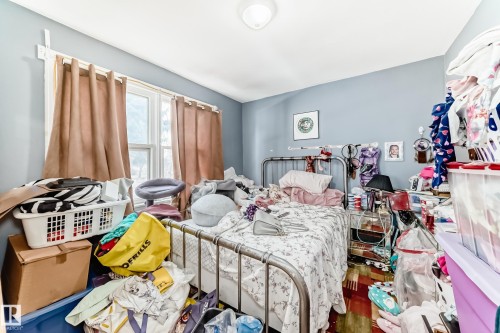 The room features a window with curtains, a ceiling light fixture, and light blue walls - 7723 82 Avenue, Edmonton, AB - Indoor Photo Showing Bedroom