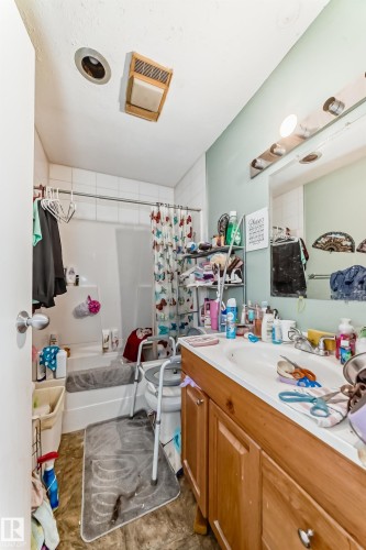 Bathroom featuring a vanity with a white countertop and a single sink, light wood cabinetry, and a mirror with overhead lighting - 7723 82 Avenue, Edmonton, AB - Indoor