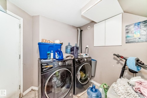 The property includes a laundry area with a washer and dryer, wall-mounted cabinetry, and a white door - 7723 82 Avenue, Edmonton, AB - Indoor Photo Showing Laundry Room