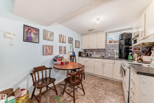 The kitchen features white cabinetry, a black refrigerator, and a white oven with an overhead microwave - 7723 82 Avenue, Edmonton, AB - Indoor Photo Showing Kitchen