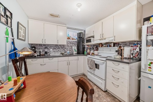 The kitchen features white cabinetry, a white stove, and a white refrigerator - 7723 82 Avenue, Edmonton, AB - Indoor Photo Showing Kitchen With Double Sink