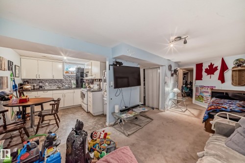 This open-concept living space features light-colored walls and a combination of carpeted and linoleum flooring - 7723 82 Avenue, Edmonton, AB - Indoor