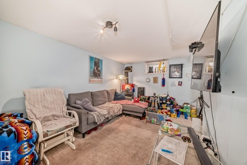 This versatile living area features light blue walls, a gray sectional sofa, and carpeted flooring - 7723 82 Avenue, Edmonton, AB - Indoor Photo Showing Living Room