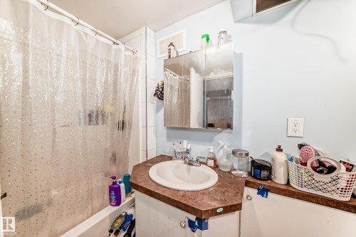 Bathroom featuring a bathtub with a shower, a vanity with an integrated sink, and a medicine cabinet with a mirrored door - 7723 82 Avenue, Edmonton, AB - Indoor Photo Showing Bathroom