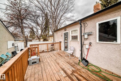 The property features an outdoor wooden deck with a wooden railing, a privacy fence, and mature trees visible in the background - 7723 82 Avenue, Edmonton, AB - Outdoor With Deck Patio Veranda With Exterior