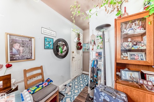 The entryway features light-colored walls and a patterned floor, with a white door and a wooden display cabinet with glass doors - 7723 82 Avenue, Edmonton, AB - Indoor