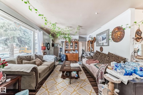 The living area features two windows, a ceiling fan, and hardwood floors - 7723 82 Avenue, Edmonton, AB - Indoor Photo Showing Living Room