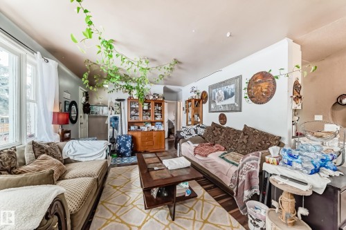 Living area featuring hardwood flooring, natural light from the window, and a wooden display cabinet - 7723 82 Avenue, Edmonton, AB - Indoor Photo Showing Living Room