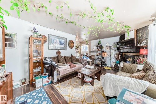 Living area featuring hardwood flooring and a fireplace with a dark stone facade - 7723 82 Avenue, Edmonton, AB - Indoor Photo Showing Living Room