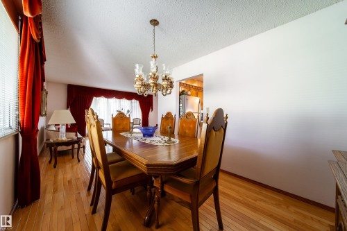 Dining area featuring wood-finish flooring, a decorative chandelier, and an open entryway to a separate room - 8509 39B Avenue, Edmonton, AB - Indoor Photo Showing Dining Room