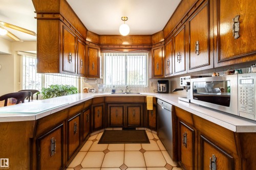 U-shaped kitchen with wood-finish cabinetry, white countertops, and a white tile floor - 8509 39B Avenue, Edmonton, AB - Indoor Photo Showing Kitchen