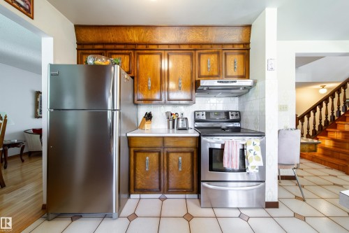 Kitchen featuring wood cabinetry, white tile backsplash, and stainless steel appliances - 8509 39B Avenue, Edmonton, AB - Indoor Photo Showing Kitchen