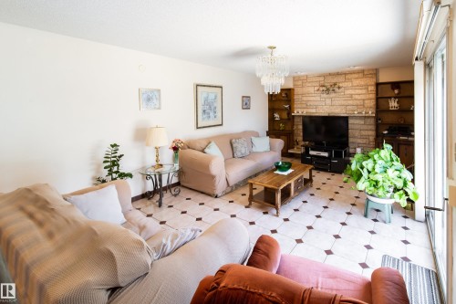 Spacious interior featuring patterned floor tile, a stone-clad fireplace, and built-in shelving - 8509 39B Avenue, Edmonton, AB - Indoor Photo Showing Living Room With Fireplace