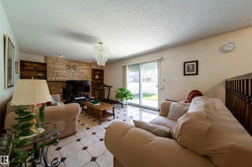 Spacious living area featuring a stone accent wall with built-in shelving, a glass chandelier, and tile flooring - 8509 39B Avenue, Edmonton, AB - Indoor Photo Showing Living Room