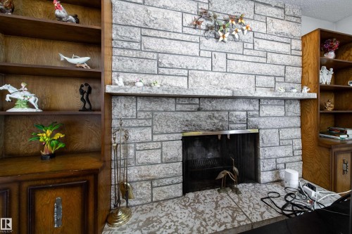 Stone-clad fireplace with a hearth, flanked by built-in wood cabinetry and shelving - 8509 39B Avenue, Edmonton, AB - Indoor With Fireplace