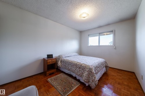 Bright bedroom featuring parquet wood-finish flooring, white walls, and a textured ceiling - 8509 39B Avenue, Edmonton, AB - Indoor Photo Showing Bedroom