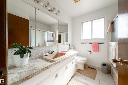 Bathroom vanity featuring an integrated sink, patterned backsplash tile, and a large wall-mounted mirror - 8509 39B Avenue, Edmonton, AB - Indoor Photo Showing Bathroom